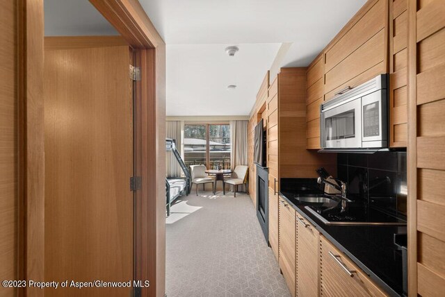 kitchen featuring black electric stovetop, sink, and wooden walls