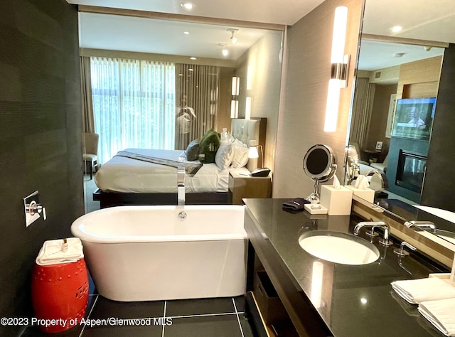 bathroom featuring a bathing tub, tile patterned flooring, a large fireplace, and vanity