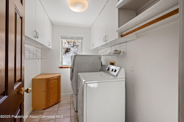 laundry room featuring cabinets, light tile patterned floors, and washing machine and clothes dryer