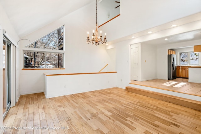 interior space with a notable chandelier, lofted ceiling, and light hardwood / wood-style flooring