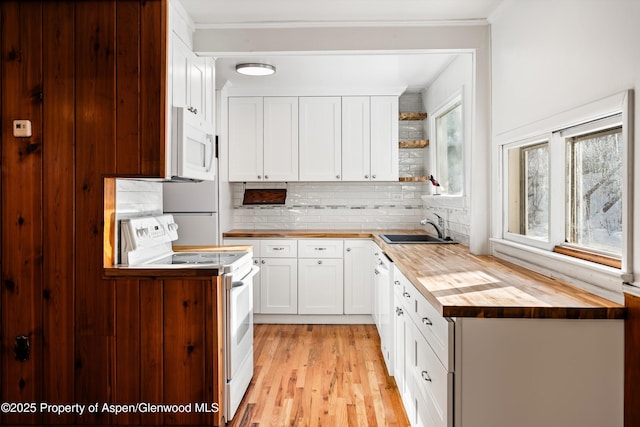 kitchen featuring white appliances, sink, tasteful backsplash, butcher block countertops, and white cabinetry