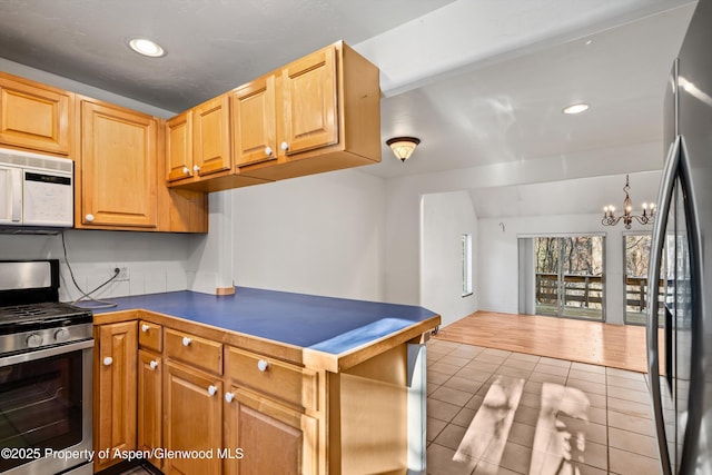 kitchen featuring hanging light fixtures, an inviting chandelier, light tile patterned flooring, and appliances with stainless steel finishes