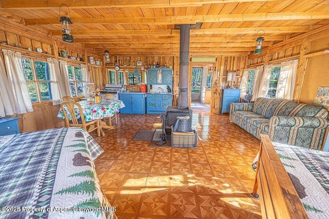 1136 Dipper Dr, Craig, CO 81625 - living area featuring wooden ceiling with exposed beams, a wood stove, and wooden walls
