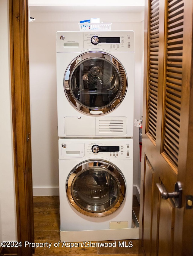 laundry room with stacked washer / dryer and dark hardwood / wood-style flooring