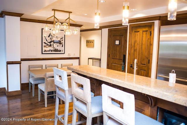 bar with stainless steel refrigerator, dark wood-type flooring, hanging light fixtures, light stone counters, and crown molding