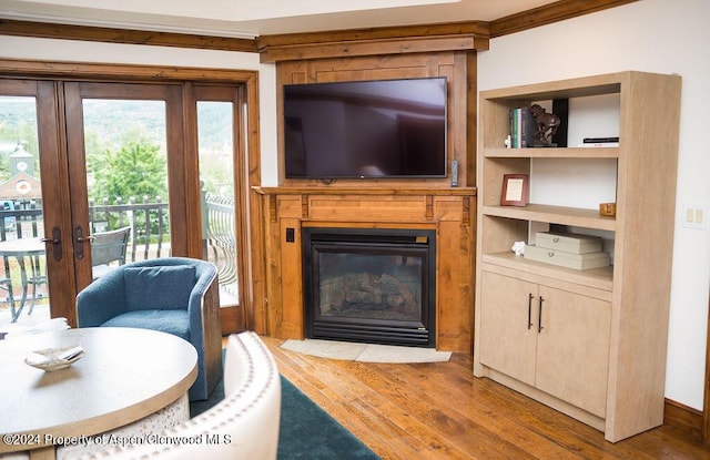 living room featuring french doors, light wood-type flooring, built in features, and crown molding