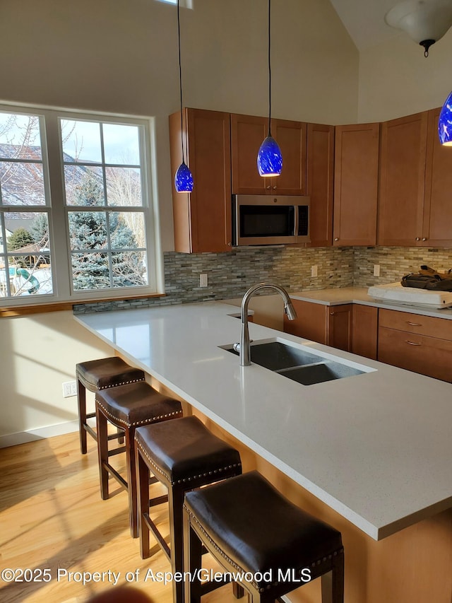1608 Crawford Way, Glenwood Springs, CO 81601 - kitchen featuring stainless steel microwave, a sink, tasteful backsplash, brown cabinetry, and light countertops