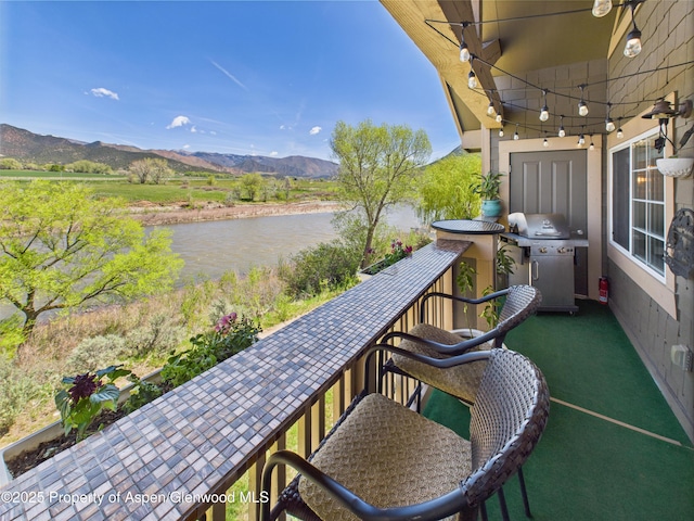 balcony with a water and mountain view and area for grilling