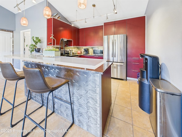 kitchen featuring a peninsula, rail lighting, a kitchen breakfast bar, decorative backsplash, and appliances with stainless steel finishes