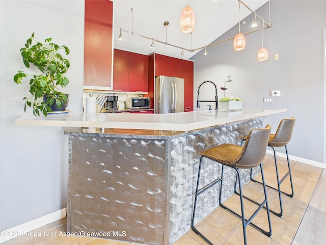 kitchen with a sink, stainless steel appliances, track lighting, baseboards, and light tile patterned flooring