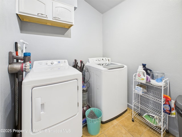 laundry area with cabinet space, washer and clothes dryer, and light tile patterned floors