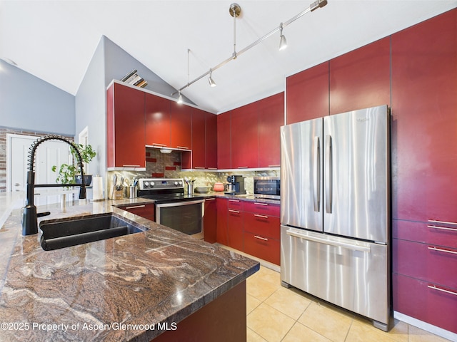 kitchen featuring a sink, stainless steel appliances, vaulted ceiling, decorative backsplash, and red cabinetry