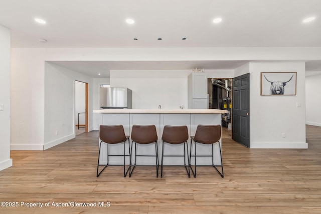 1600 County Road 30, Craig, CO 81625 - kitchen featuring baseboards, freestanding refrigerator, a kitchen breakfast bar, light wood-style flooring, and recessed lighting