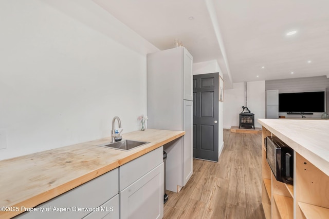 1600 County Road 30, Craig, CO 81625 - kitchen featuring a sink, a wood stove, white cabinets, light wood-style flooring, and open floor plan