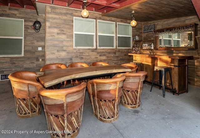 bar featuring concrete flooring, wooden ceiling, and wooden walls