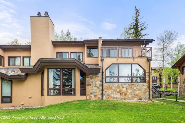 back of property with a balcony and a lawn