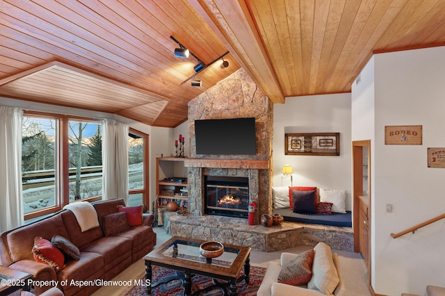 living room featuring a stone fireplace, lofted ceiling, carpet flooring, track lighting, and wooden ceiling