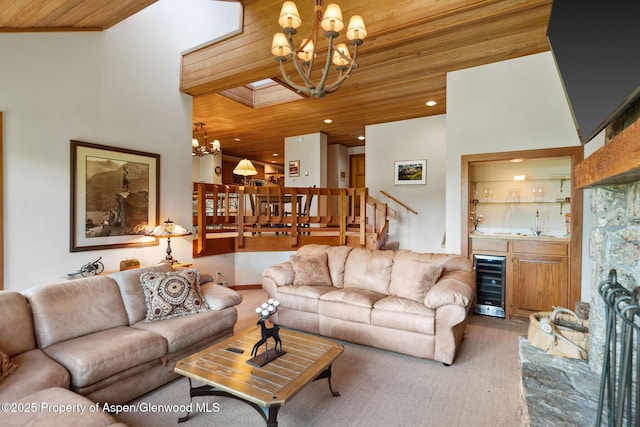 living room featuring bar, an inviting chandelier, wood ceiling, crown molding, and beverage cooler