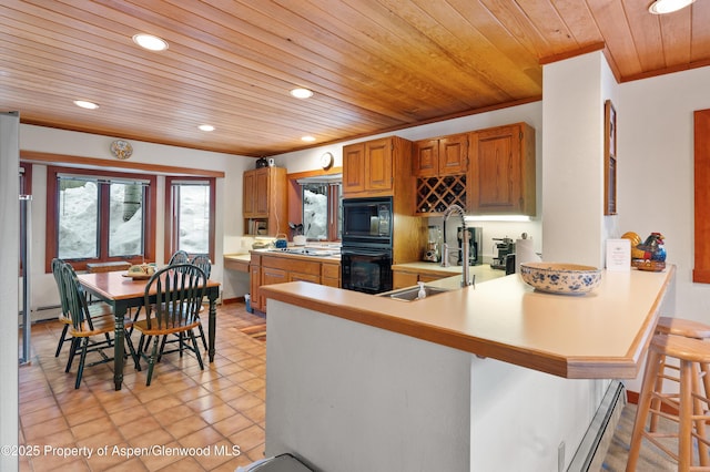 kitchen featuring a kitchen bar, sink, baseboard heating, kitchen peninsula, and black appliances