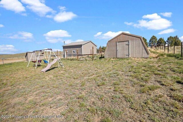 view of yard featuring a playground, a shed, and an outdoor structure
