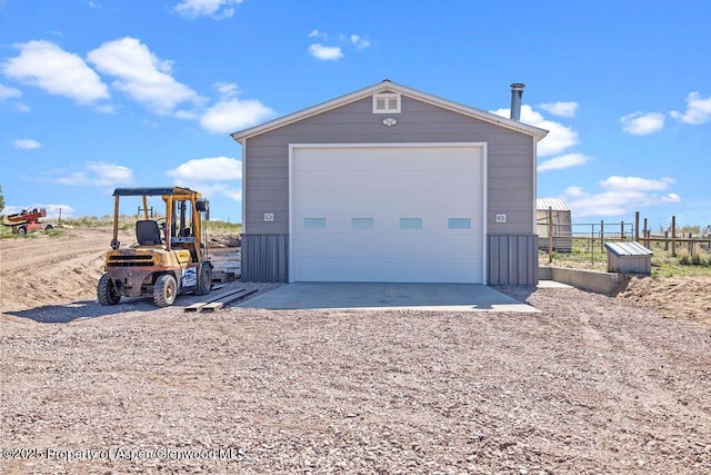 detached garage featuring fence and driveway