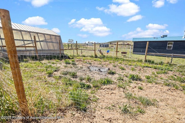 view of yard with a greenhouse, fence, and an outbuilding