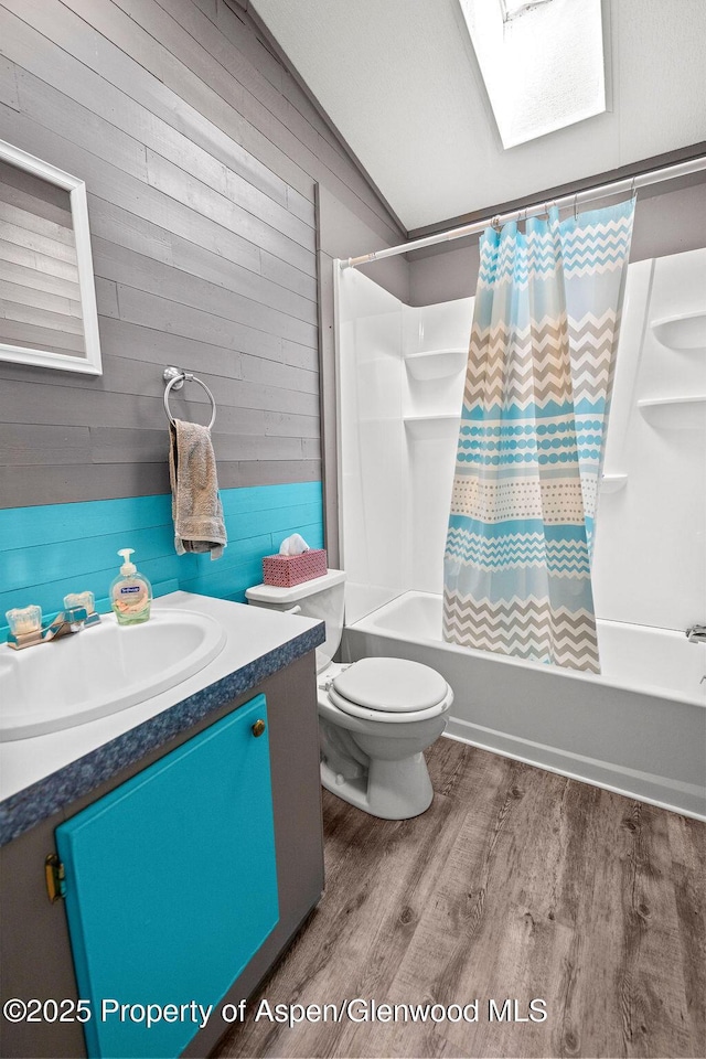 bathroom with shower / bathtub combination with curtain, vanity, wooden walls, wood finished floors, and toilet