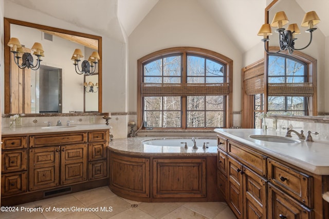 bathroom featuring an inviting chandelier, tile patterned flooring, a tub to relax in, lofted ceiling, and vanity