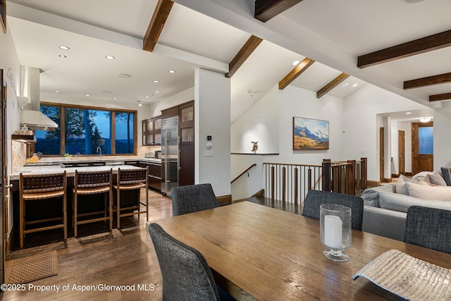 dining room featuring dark hardwood / wood-style flooring, sink, and vaulted ceiling with beams