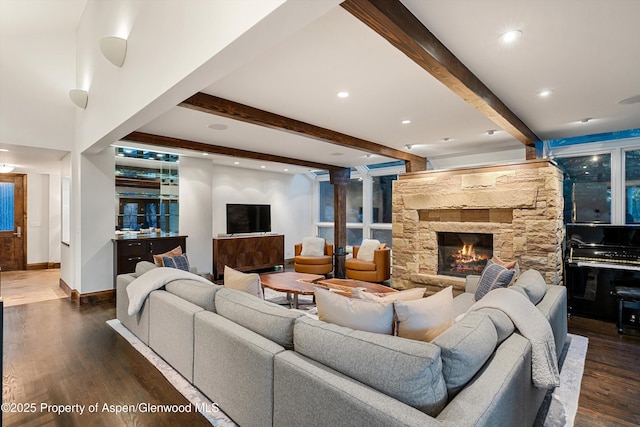 living room featuring dark hardwood / wood-style flooring, beam ceiling, and a stone fireplace