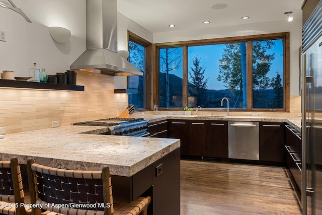 kitchen with high quality appliances, wood-type flooring, tasteful backsplash, island exhaust hood, and dark brown cabinetry