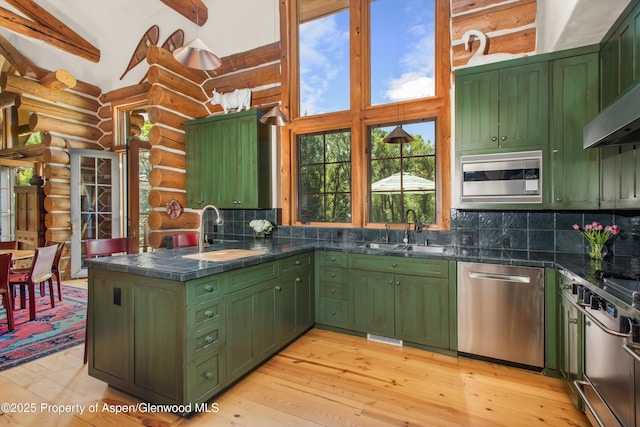 408 Gerbaz Way, Snowmass, CO 81654 - kitchen featuring green cabinetry, appliances with stainless steel finishes, log walls, wall chimney range hood, and high vaulted ceiling