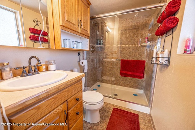 bathroom featuring tile patterned flooring, toilet, an enclosed shower, and vanity