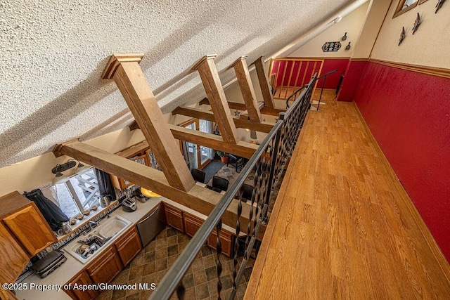 staircase with hardwood / wood-style floors and a textured ceiling