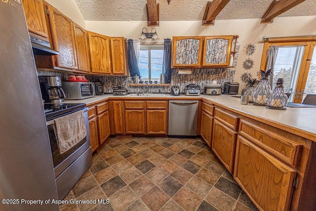 kitchen with decorative backsplash, beam ceiling, a wealth of natural light, and appliances with stainless steel finishes