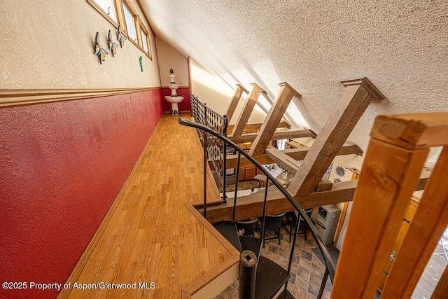 stairway with wood-type flooring and a textured ceiling