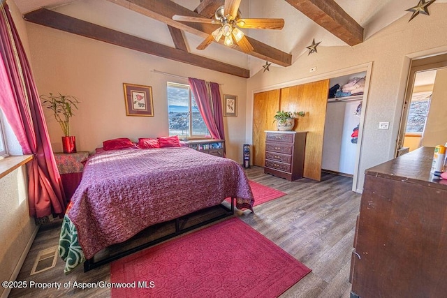 bedroom with lofted ceiling with beams, ceiling fan, wood-type flooring, and a closet