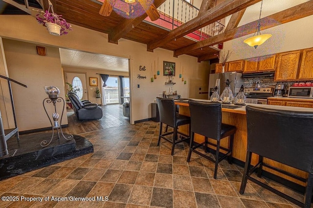 kitchen with appliances with stainless steel finishes, a breakfast bar, extractor fan, ceiling fan, and beam ceiling