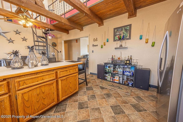 kitchen with beamed ceiling, ceiling fan, stainless steel fridge, and wood ceiling