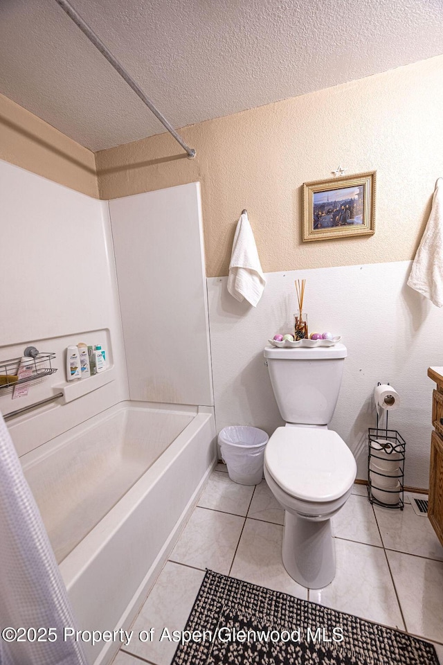 full bathroom featuring vanity, a textured ceiling, shower / tub combo with curtain, tile patterned flooring, and toilet