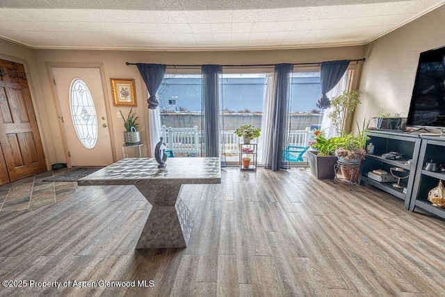 foyer entrance featuring light hardwood / wood-style floors, crown molding, and a wealth of natural light