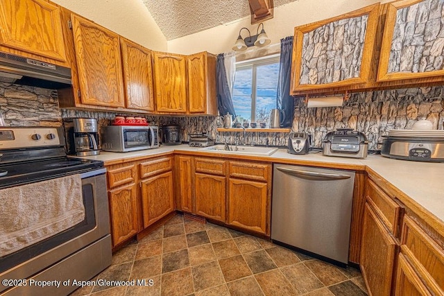 kitchen featuring decorative backsplash, stainless steel appliances, vaulted ceiling, sink, and exhaust hood