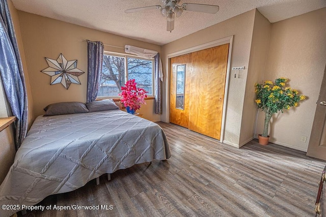 bedroom with ceiling fan, wood-type flooring, a textured ceiling, and a closet