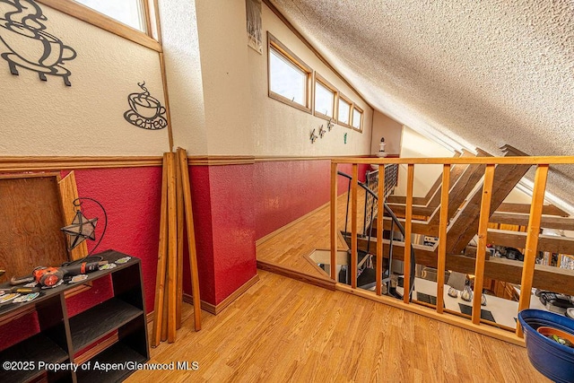 stairway with a textured ceiling and hardwood / wood-style flooring