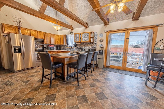 kitchen with appliances with stainless steel finishes, ceiling fan, high vaulted ceiling, hanging light fixtures, and a breakfast bar area