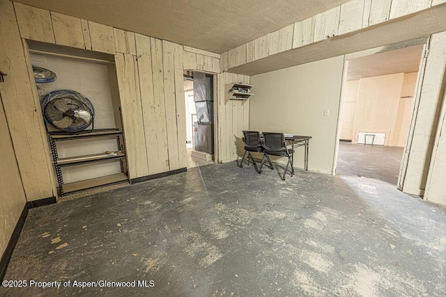 interior space with a textured ceiling and wood walls