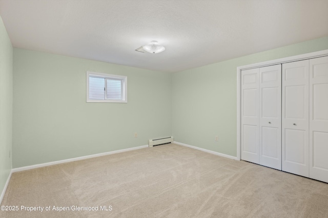 unfurnished bedroom featuring light colored carpet, baseboard heating, and a closet