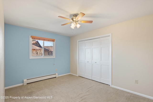 unfurnished bedroom featuring baseboard heating, ceiling fan, a closet, and light carpet