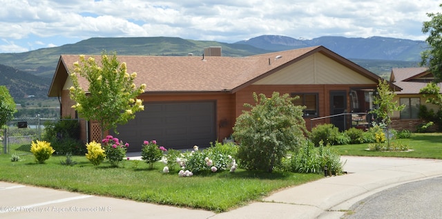 view of front of home featuring a mountain view, a garage, and a front yard