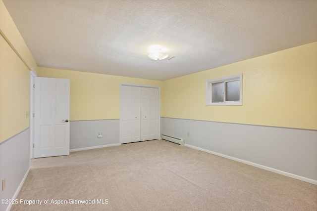 unfurnished bedroom with light carpet, a closet, a baseboard radiator, and a textured ceiling